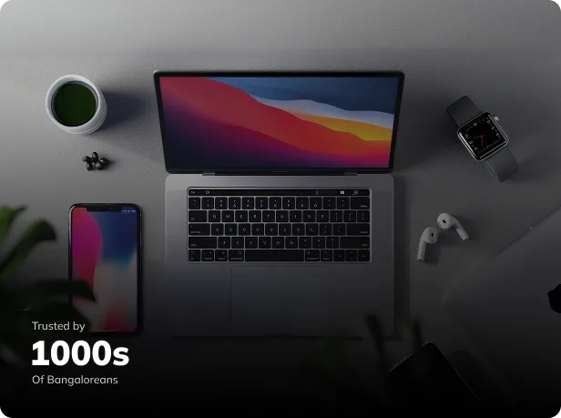 ICare Plus Apple device repair workspace featuring a MacBook, iPhone, Apple Watch, and AirPods on a clean desk, trusted by thousands of Bangalore users.